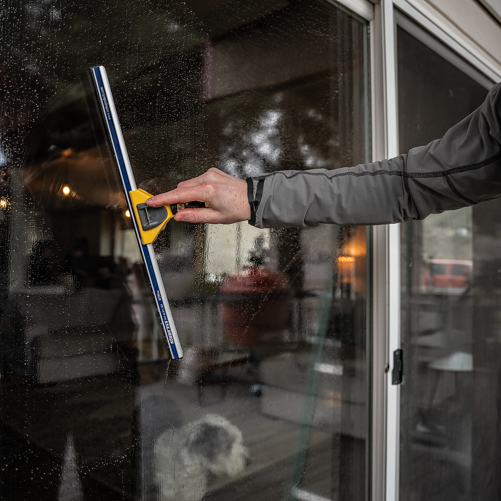 TOPRUNG cleaner working behind wet residential glass