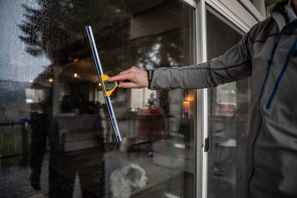TOPRUNG cleaner working inside a home viewed through sparkling clean glass