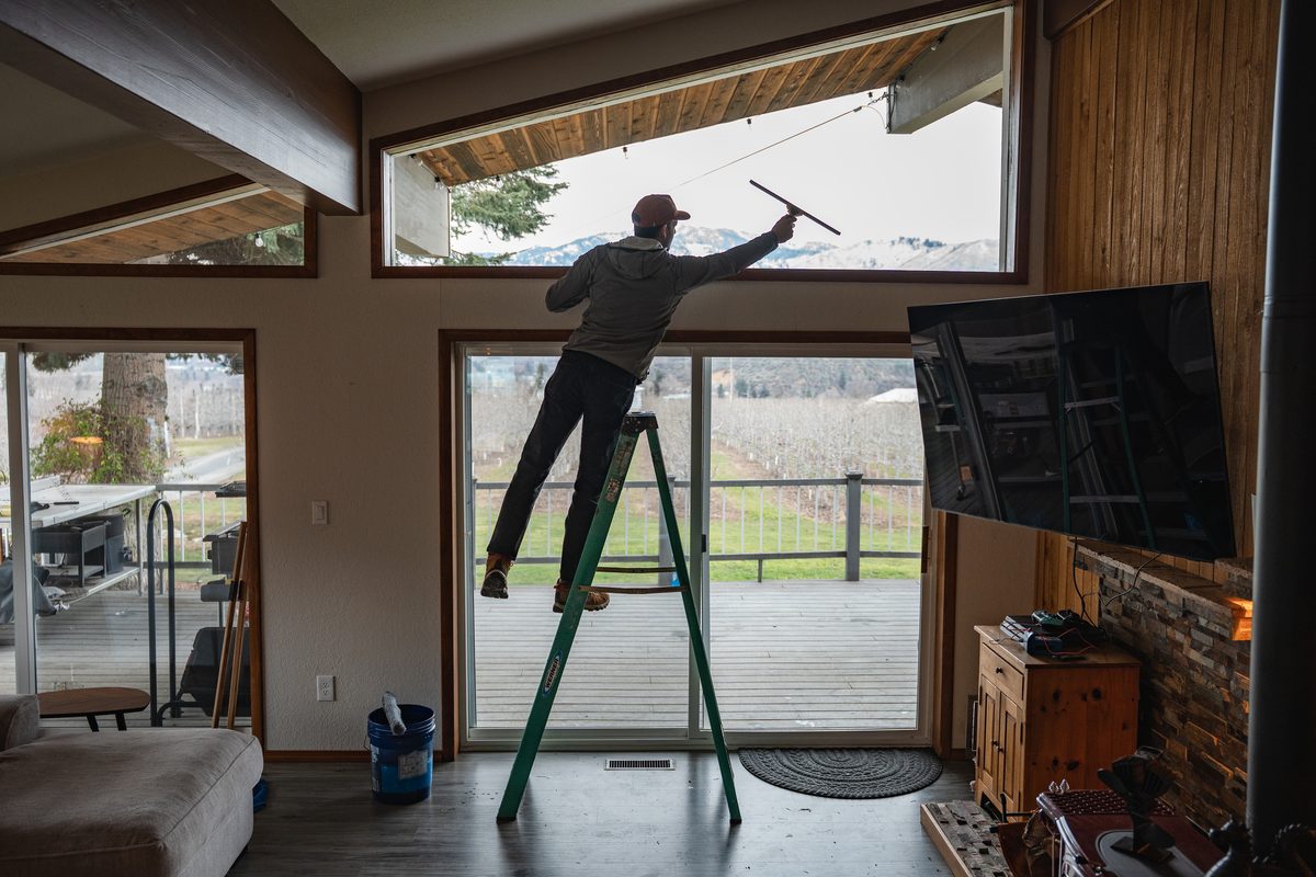 TOPRUNG cleaner reaching high with extension pole to clean windows inside a spacious home