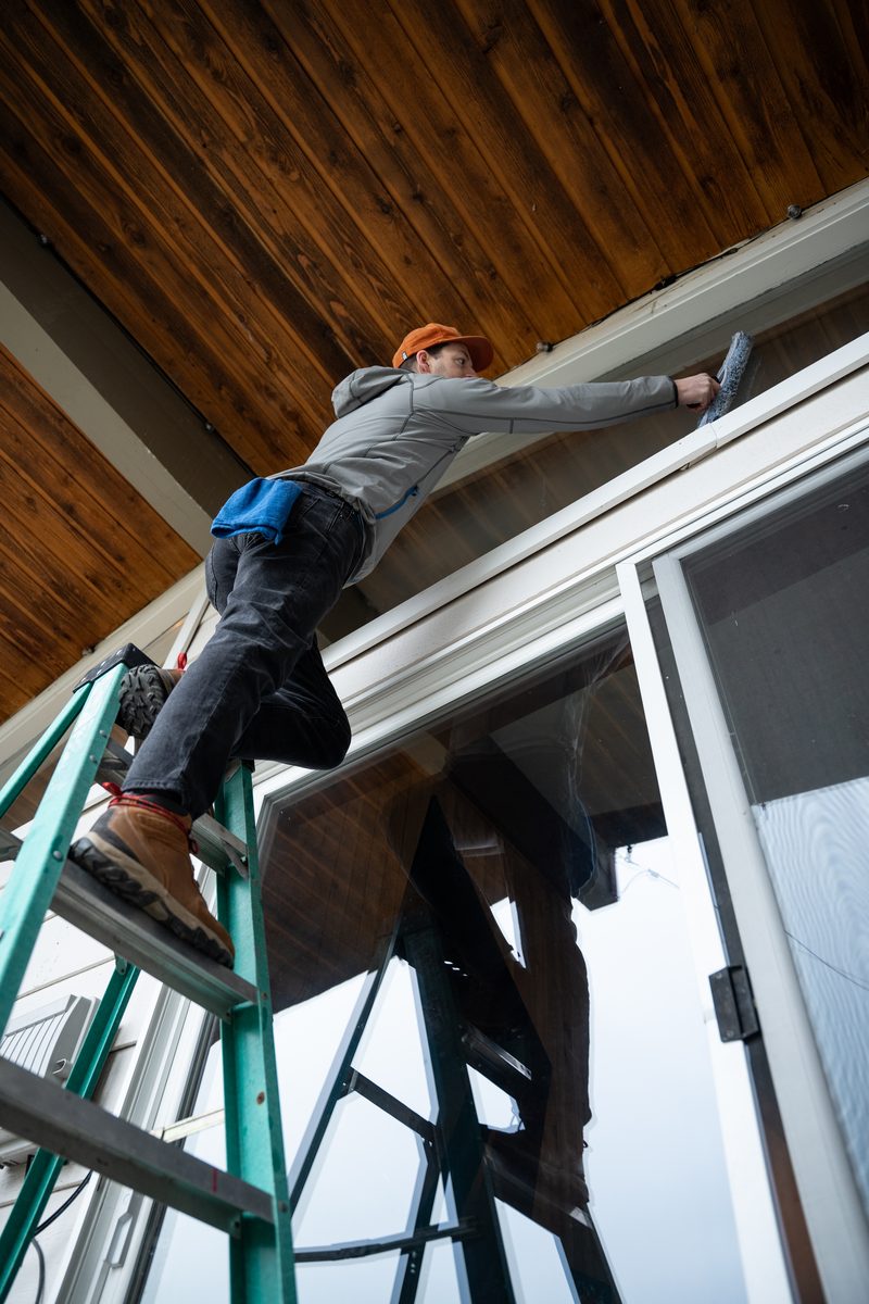TOPRUNG cleaner on ladder working on exterior of home