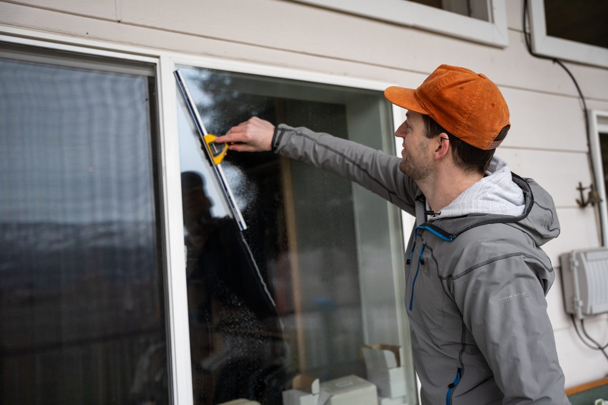 TOPRUNG cleaner using professional squeegee technique on a glass door