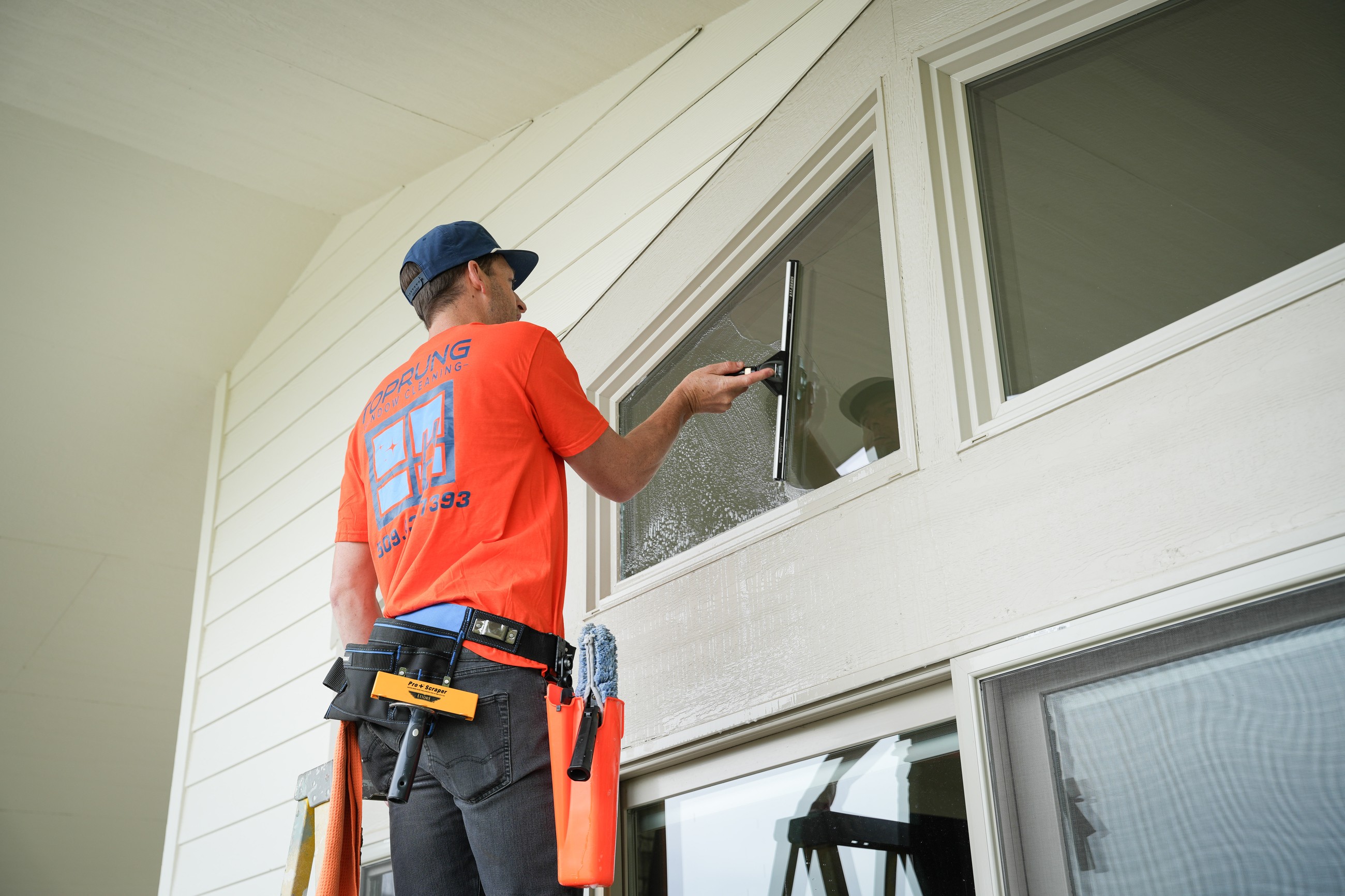 TOPRUNG technician cleaning exterior residential windows in uniform